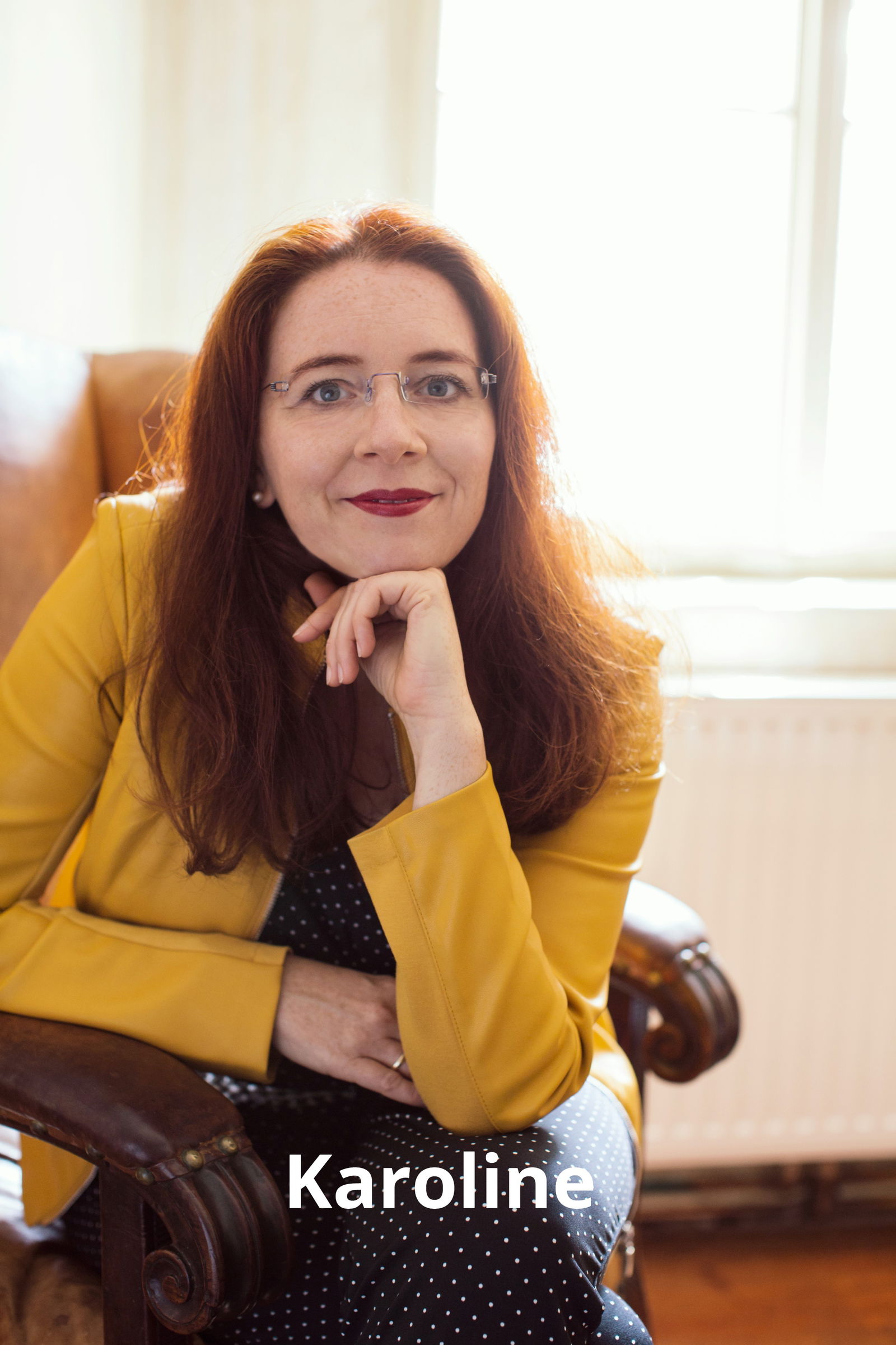 Karoline – Trainerin und Coach für Selbstwert, Kommunikation und Karriereentwicklung, freundlich lächelnd im Sessel sitzend