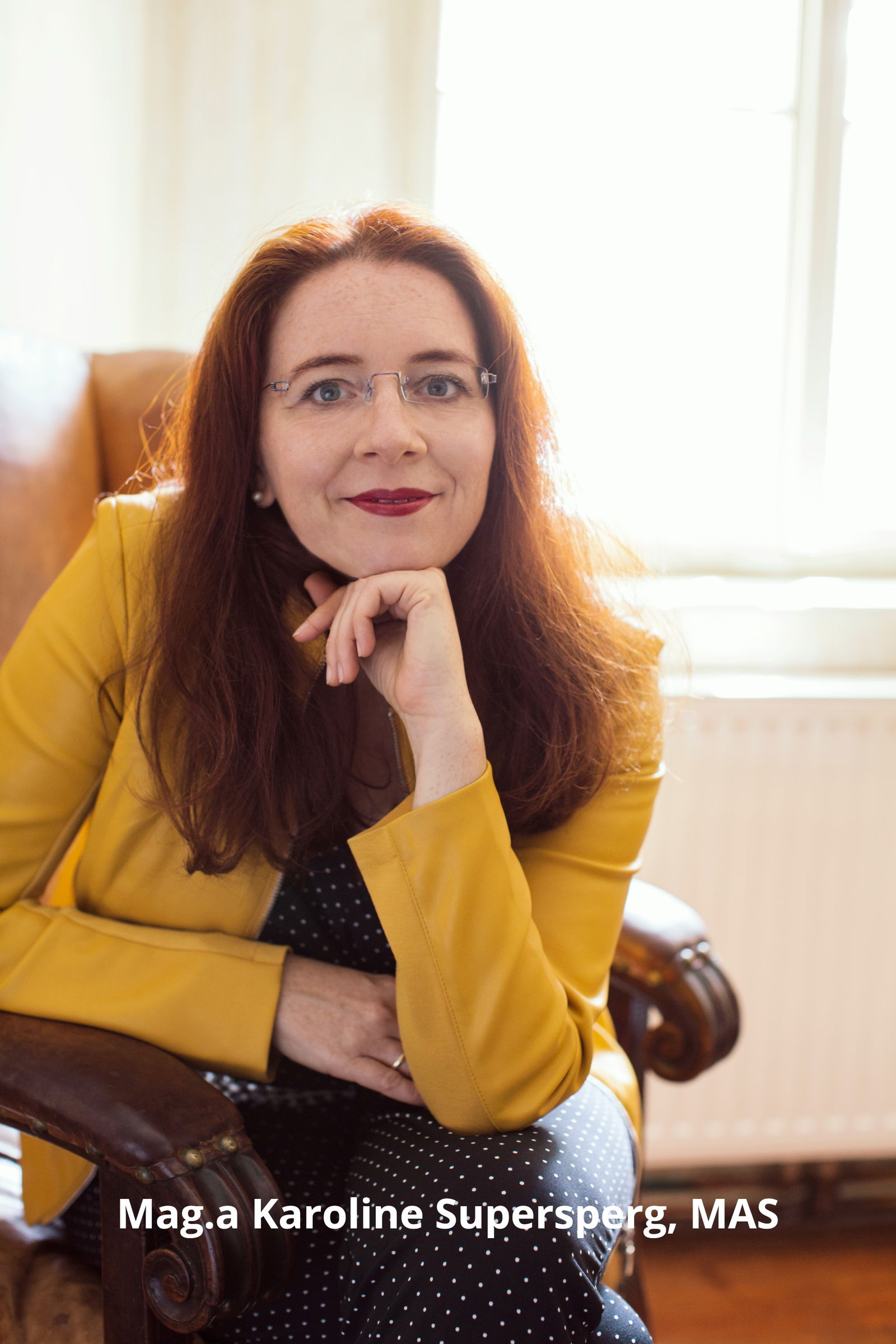 Mag.a Karoline Supersperg, MAS – Trainerin und Coach für Selbstwert, Kommunikation und Karriereentwicklung, freundlich lächelnd im Sessel sitzend